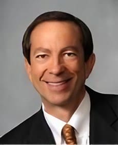 A man in suit and tie smiling for the camera.