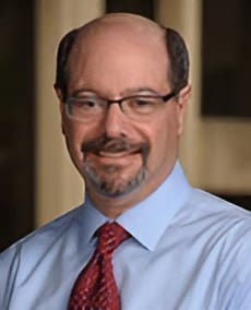 A man with glasses and a beard wearing a blue shirt